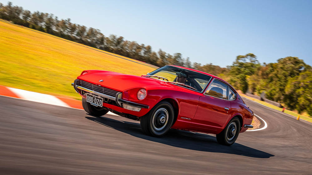 rouge vue de 3/4 avant gauche roule sur un circuit et prend un virage