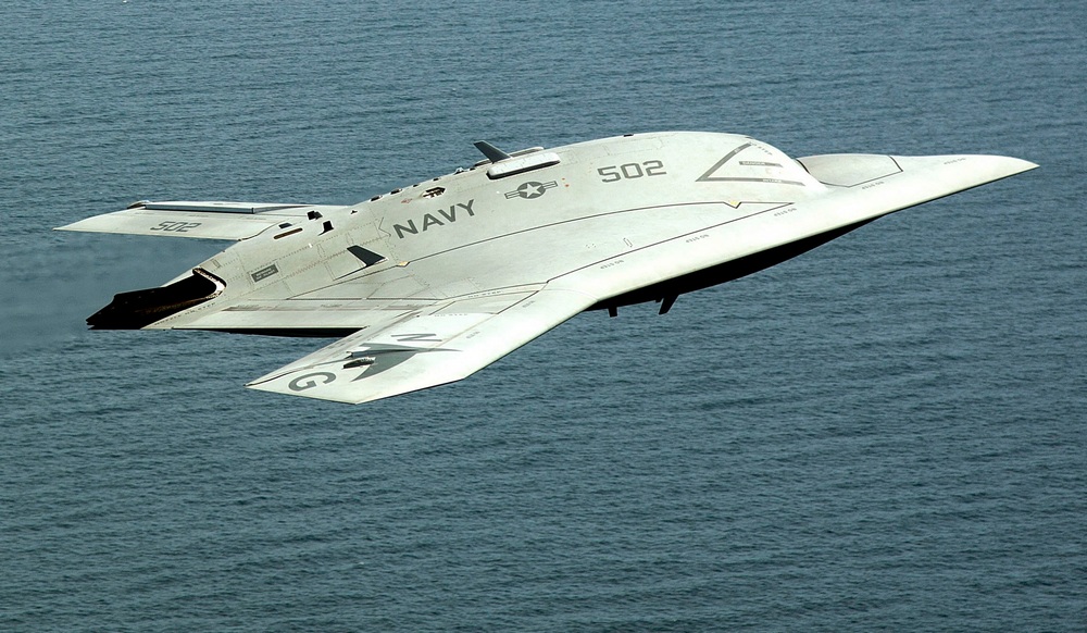 un X-47B en vol au-dessus de la mer, vu de profil droit