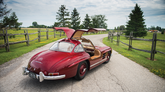 une Mercedes-Benz 300 SL (W198) 1954 rouge, portières ouvertes, vue de 3/4 arrière droit