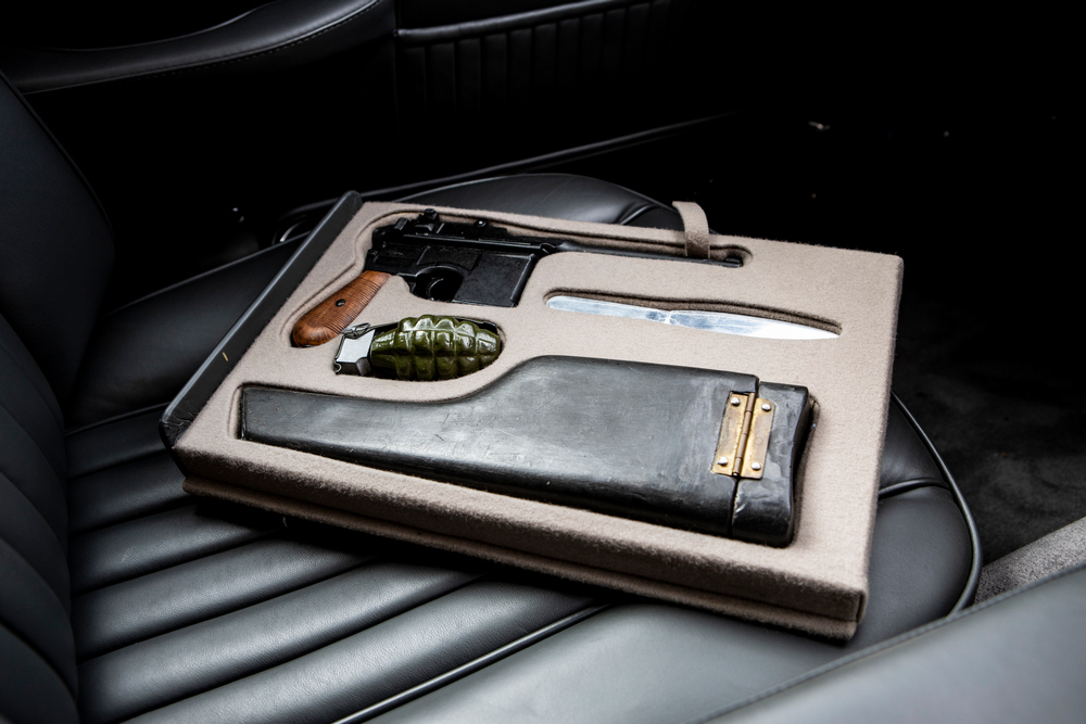 les outils indispensables de James Bond (un pistolet, un holster, un couteau et une grenade) rangés dans un coffret posé sur le siège avant