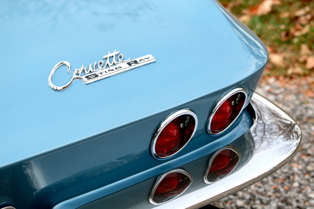 la Chevrolet Corvette Sting Ray (C2) 1963, bleu clair, zoom sur l'insigne de la marque arrière, les feux et le pare-chocs