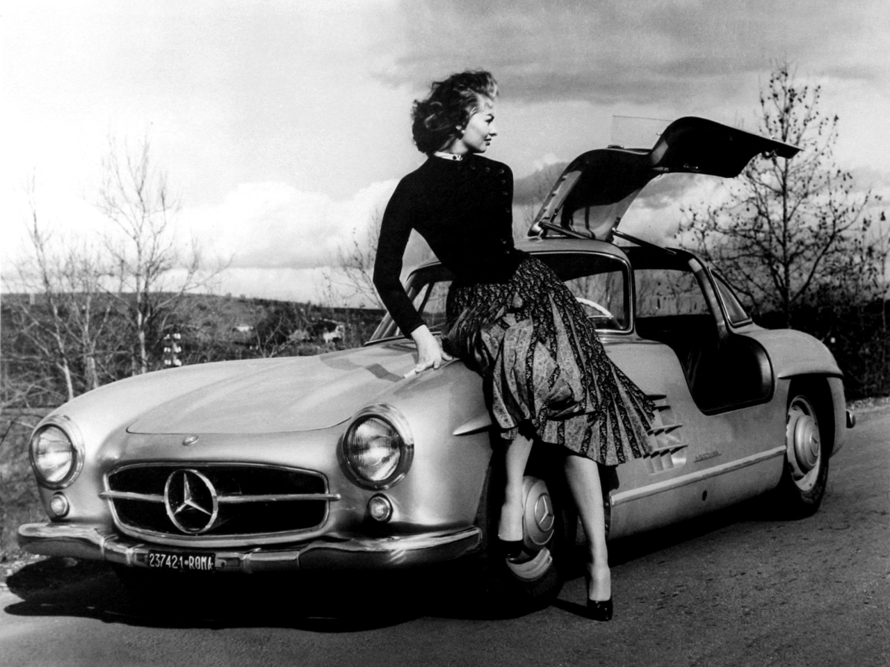la Mercedes-Benz 300 SL vue de 3/4 avant gauche, portière ouverte avec Sophia Loren assis sur l'aile gauche