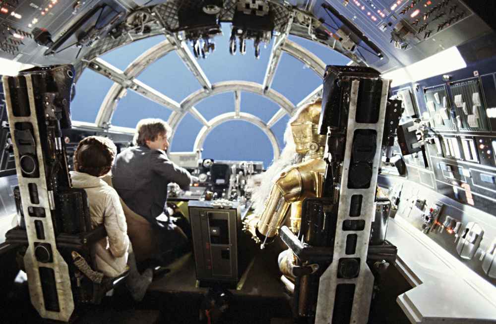 les coulisses du cockpit avec Han, Chewbacca, C-3PO et Leia vus de dos