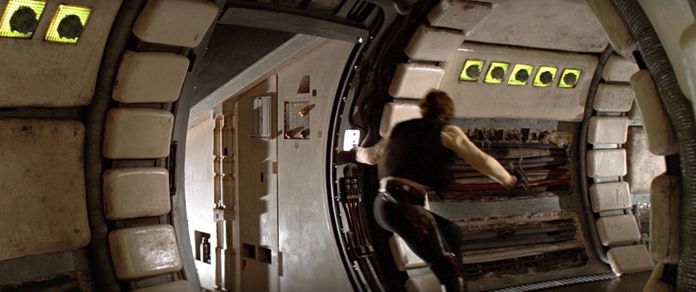 Han Solo à l'entrée du couloir devant la rampe ouverte appuie sur le bouton pour fermer la porte de la rampe