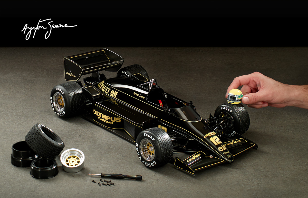 la Lotus 97T, des pièces sur la gauche, une main pose un casque sur la roue de la maquette à droite